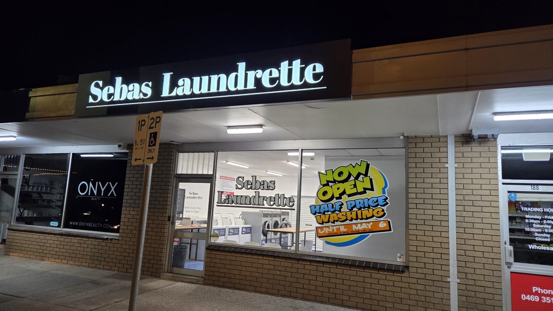 Sebas Laundrette shopfront at night with its illuminated sign on Albert Street