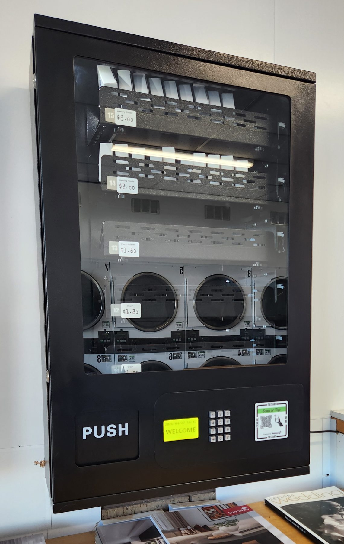 Wall-mounted vending machine stocked with washing powder, fabric softener and bleach