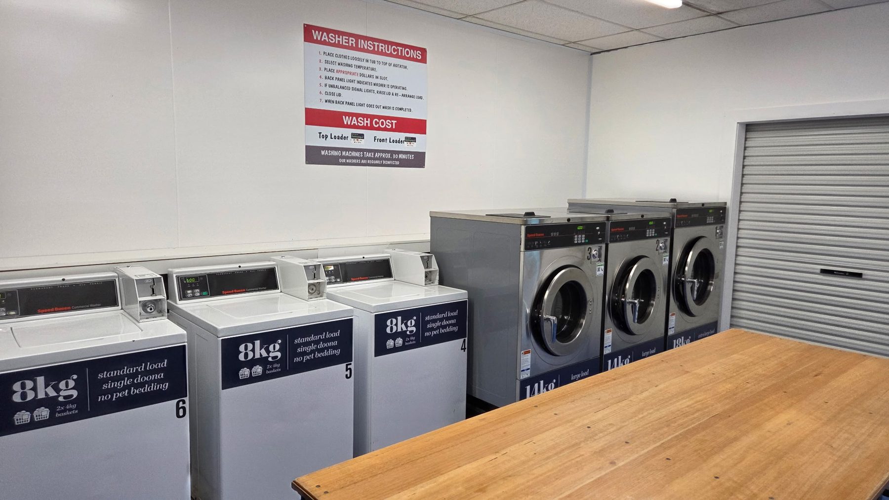 Row of 8kg top-loading washers and large front loaders beside the folding table